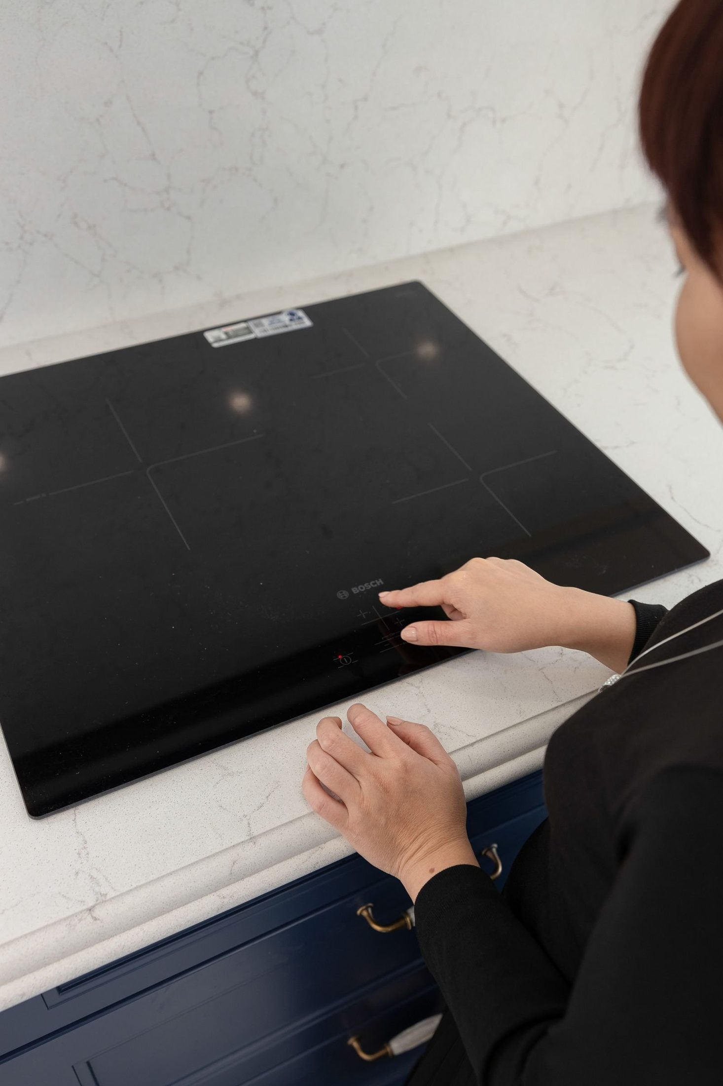 Hand resting on a modern induction cooktop